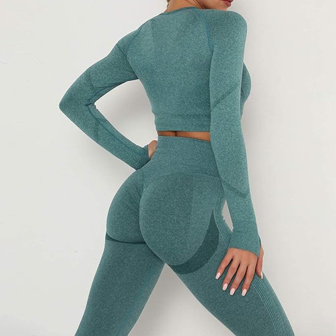Laad afbeelding in Galerijviewer, Een persoon in een blauwgroene outfit met lange mouwen uit de 3-delige yoga workoutset, gemaakt van slijtvaste stof, staat bij een witte muur met één hand op de heup, en legt moeiteloze elegantie vast.
