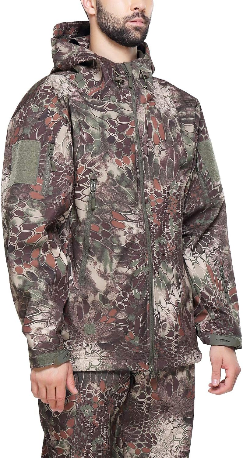 Laad afbeelding in Galerijviewer, Een persoon staat tegen een witte achtergrond, de handen langs het lichaam, gekleed in een camouflage tactische heren softshell jas: de perfecte metgezel voor je outdoor-avonturen en een bijpassende broek met capuchon.

