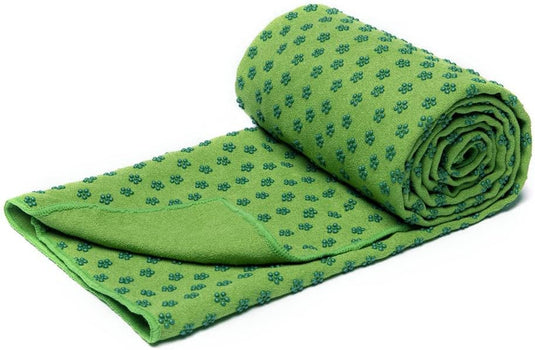Een opgerolde groene yogahanddoek met blauwe bloemenpatronen, uitgevoerd als antislip yogahanddoek in extra groot formaat, verbetert jouw yoga-ervaring!.