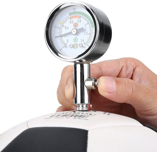 Een hand houdt de mini luchtdrukmeter vast en meet optimaal de luchtdruk van een zwart-witte sportbal.