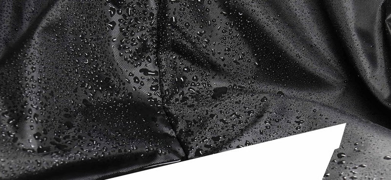Laad afbeelding in Galerijviewer, Close-up van de zwarte waterdichte stof van de premium roeimachine hoes, voorzien van waterdicht 210D Oxford-doek met regendruppels die op het oppervlak parelen, wat de waterbestendige eigenschappen aantoont.
