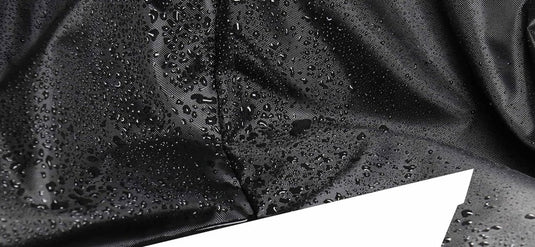 Close-up van de zwarte waterdichte stof van de premium roeimachine hoes, voorzien van waterdicht 210D Oxford-doek met regendruppels die op het oppervlak parelen, wat de waterbestendige eigenschappen aantoont.