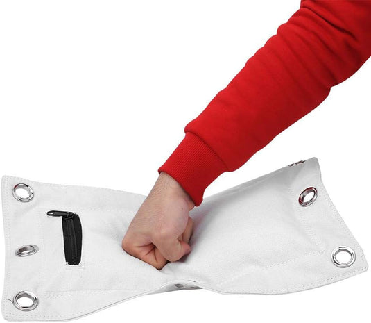 Iemand raakt een flexibel wit vinylzeil, dat lijkt op de "Ontdek de kracht van de triple bag: De ultieme trainingspartner voor boksen, thaiboksen en kungfu!" met metalen oogjes en een klein zwart zakje met ritssluiting.