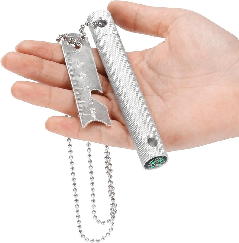 Laad afbeelding in Galerijviewer, Een hand die de Robuuste vuurstarter vasthoudt, met een liniaal, ketting, kompas en cilindervormig handvat, ideaal voor elk buitenavontuur.
