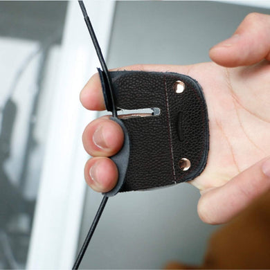 Een hand houdt een eersteklas zwarte leren boogschiet vingerbescherming vast, gemaakt van hoogwaardig rundleder met metalen klinknagels en een centrale gleuf, die stijl en bruikbaarheid combineert voor verbeterde prestaties.