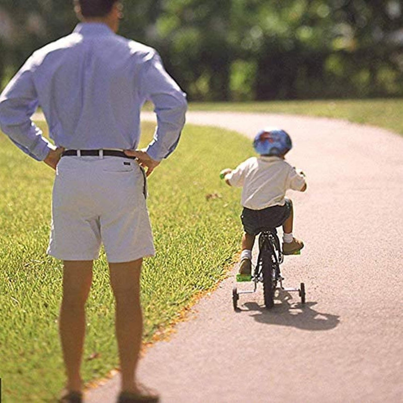 Laad afbeelding in Galerijviewer, Een volwassene kijkt hoe een kind met een helm op fietst met &quot;Zijwieltjes voor kinderfietsen: De veilige start van hun fietsplezier!&quot; op een parkpad, waardoor de veiligheid gegarandeerd is.
