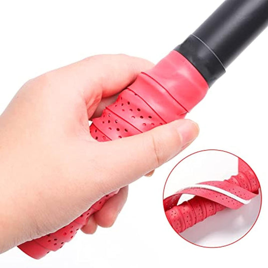 Hand houdt een rackethandvat vast met een rode, geperforeerde grip uit de Padel grip set: personaliseer je racket en verbeter je spel. Inzet toont de close-up van de textuur en wikkeling, met de nadruk op verbeterde grip.