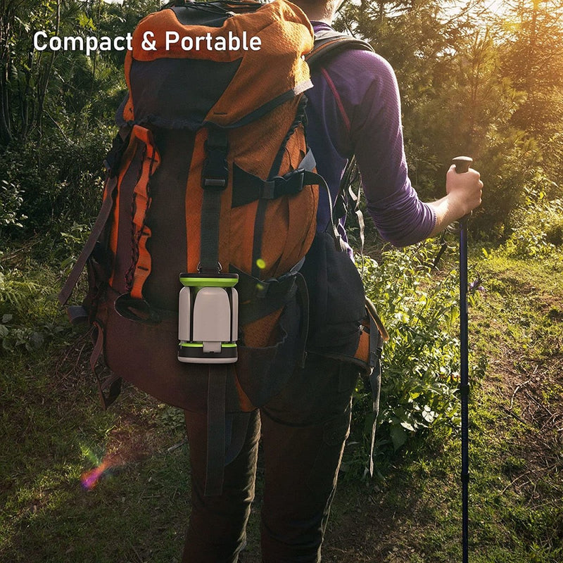 Laad afbeelding in Galerijviewer, Een persoon die in een bosrijke omgeving wandelt met een grote oranje en zwarte rugzak, een wandelstok en de &quot;Waterdichte en schokbestendige campinglamp voor buitenactiviteiten&quot; onder de tekst &quot;Compact &amp; Portable.
