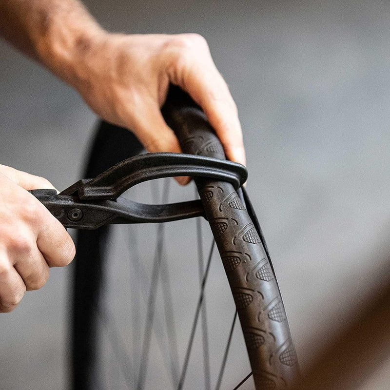 Laad afbeelding in Galerijviewer, Vaardige handen gebruiken de &quot;Maak het wisselende van banden eenvoudig met onze bandentang voor fietsen&quot; om een fietsband aan te brengen of af te stellen voor een universele pasvorm, waardoor soepele ritten worden gegarandeerd.
