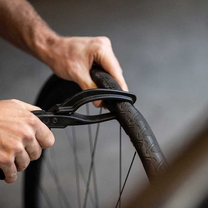 Laad afbeelding in Galerijviewer, Handen maken vakkundig gebruik van onze &quot;Maak het wisselen van banden eenvoudig met onze bandentang voor fietsen!&quot; om behendig een fietsband van de velg te verwijderen.
