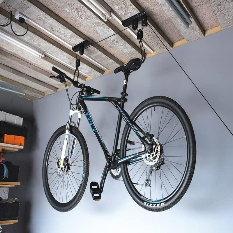 Laad afbeelding in Galerijviewer, Een zwart-witte mountainbike wordt ondersteboven aan het plafond van een garage gehangen met behulp van de &quot;Optimaliseer uw ruimte en bescherm uw fiets met de innovatieve fietslift.
