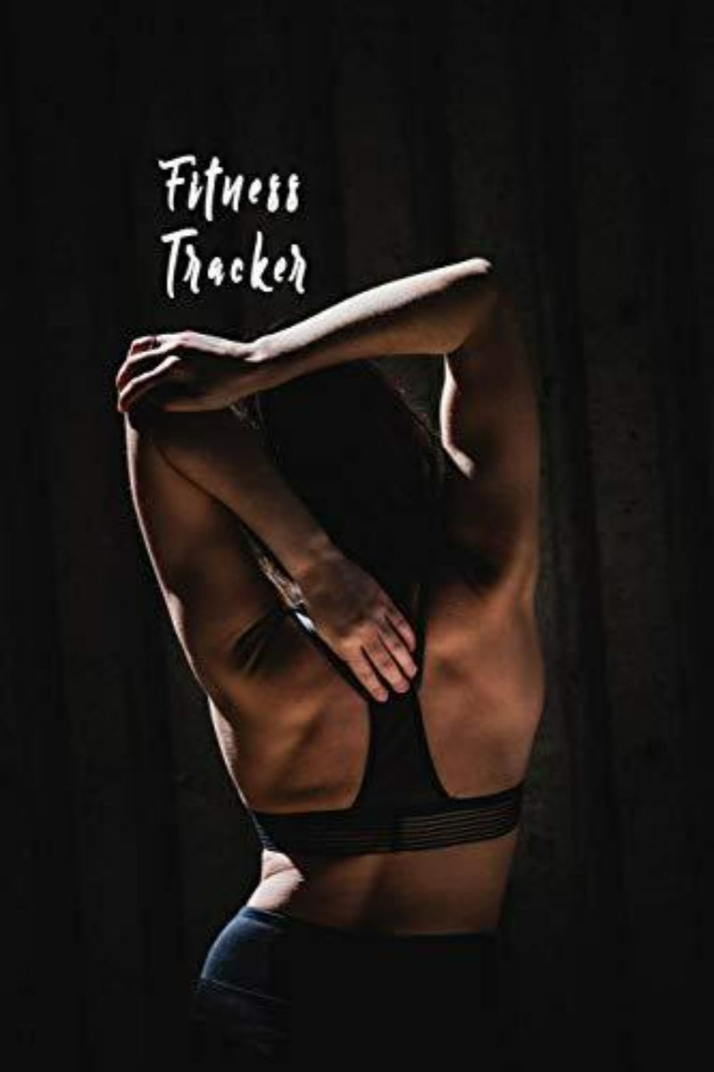 Laad afbeelding in Galerijviewer, In een slecht verlichte kamer strekt een persoon zich sierlijk uit in een sportbeha. Een &quot;Fitness Tracker: Logboek Ongedateerde Dagelijkse Training Gym of Outdoor Workout Journal Notebook&quot; integreert moeiteloos met elke beweging, waardoor fitness-inschrijvingen een kunstvorm worden.
