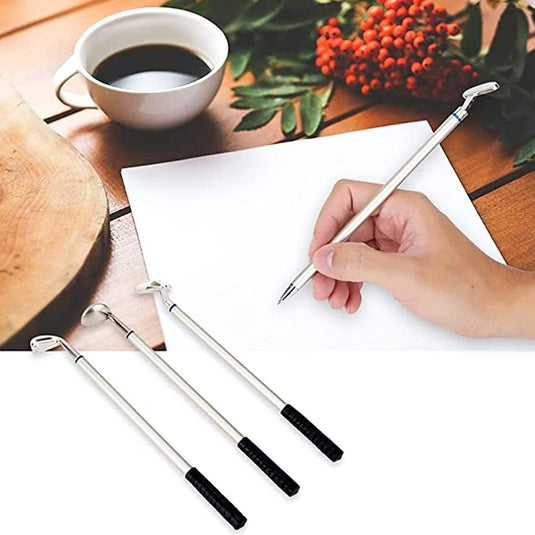 Schrijven op papier met een pen uit de Golfclub pennenset, samen met drie bijpassende pennen en een koffiekopje op een houten oppervlak, met rode bessen en groene bladeren op de achtergrond.
