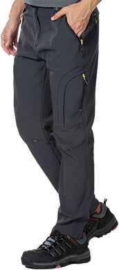 Een persoon gekleed in de Houd je warm en comfortabel wandel en skibroek, donkergrijs met ritsen, gecombineerd met zwarte wandelschoenen met rode accenten, is klaar voor elk avontuur.