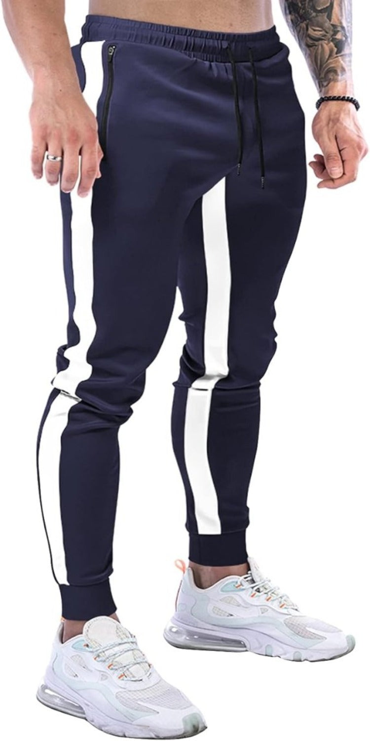 Laad afbeelding in Galerijviewer, Een man die een marineblauwe joggingbroek voor heren draagt met witte zijstrepen en witte sneakers straalt een stijlvolle uitstraling uit, waarbij zijn getatoeëerde arm goed tot zijn recht komt.
