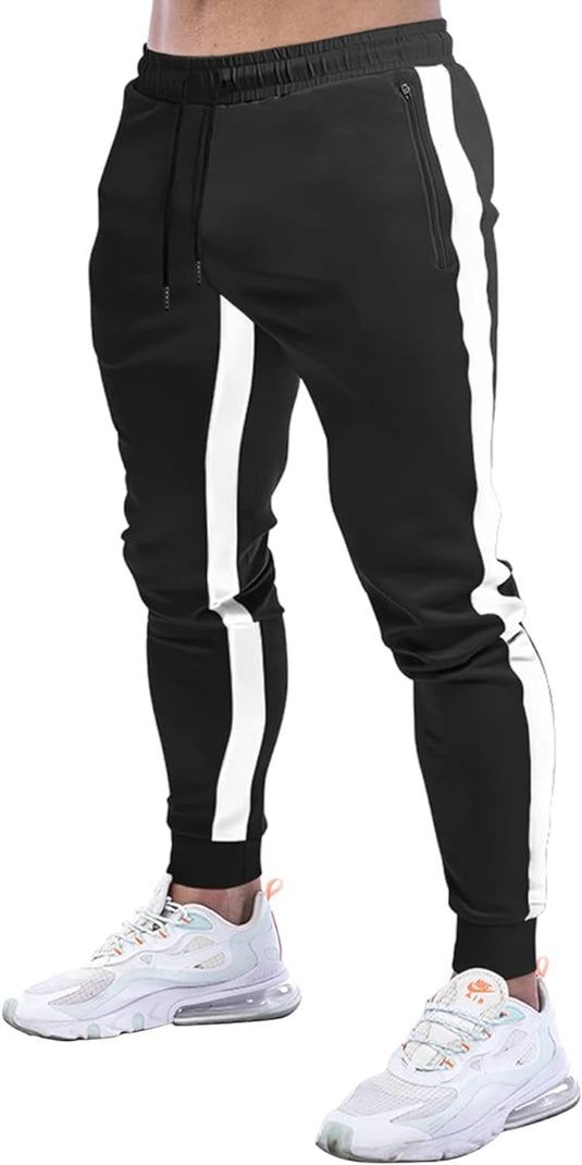 Persoon in een stijlvolle uitstraling, gekleed in een zwarte "Joggingbroek voor heren" met witte zijstrepen, gecombineerd met witte sneakers.