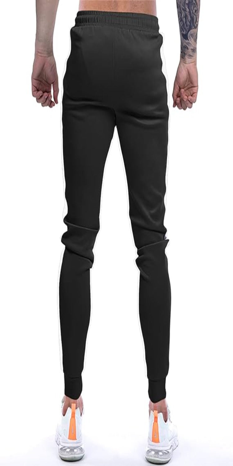Laad afbeelding in Galerijviewer, Een man met zijn rug naar de camera showt zijn Joggingbroek voor heren in het zwart, gecombineerd met witte sneakers met oranje accenten voor een stijlvolle uitstraling.
