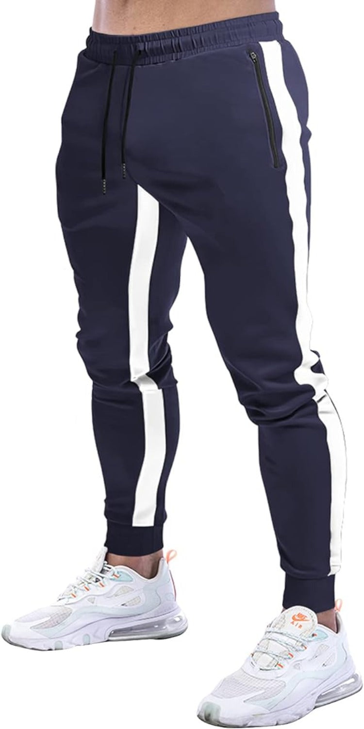 Laad afbeelding in Galerijviewer, Een man straalt een stijlvolle uitstraling uit in de Joggingbroek voor heren: comfortabel, duurzaam en stijlvol in navy met frisse witte verticale strepen, moeiteloos gecombineerd met ademende witte sneakers.
