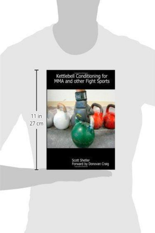 Een persoon houdt "Kettlebell Conditioning for MMA and Other Fight Sports" van Scott Shetler vast, met kettlebell-afbeeldingen op de cover. Dit 11-inch hoge boek is ideaal voor fans van vechtsporten en is een belangrijke bron voor het verbeteren van MMA-training.