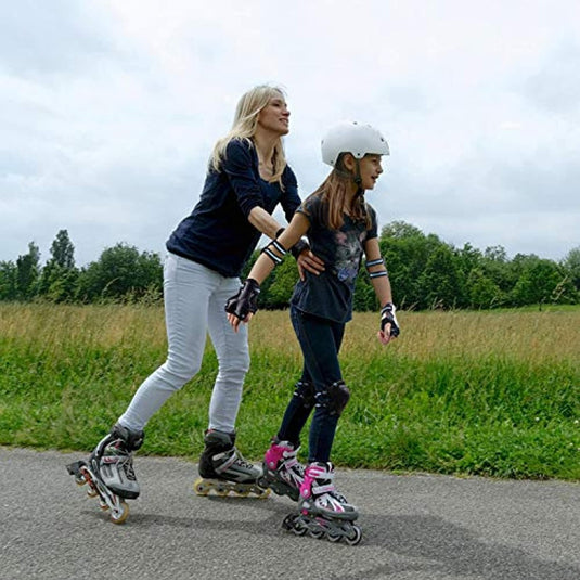 Een volwassene en een kind, uitgerust met helmen en het "Bescherm je kind tijdens het sporten met deze complete set skeeler bescherming", glijden moeiteloos samen over een verhard parkpad.