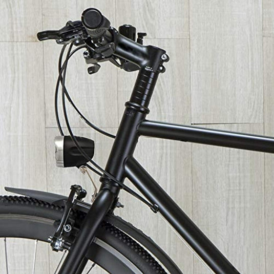 Een close-up van een zwart fietsframe en stuur tegen een lichte muur met houtstructuur, met kabels en een koplamp die door StVZO is goedgekeurd voor veiligheid en energie-efficiëntie met een helderheid van 30 lux.
