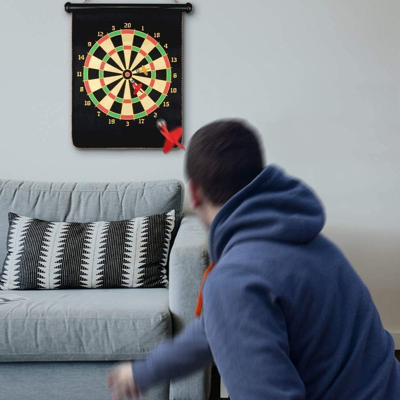 Laad afbeelding in Galerijviewer, Een persoon in een blauwe hoodie gooit een dartpijltje naar het Dubbelzijdige magnetische dartbord dat boven een grijze bank hangt, wat plezier en veiligheid voor alle leeftijden garandeert.
