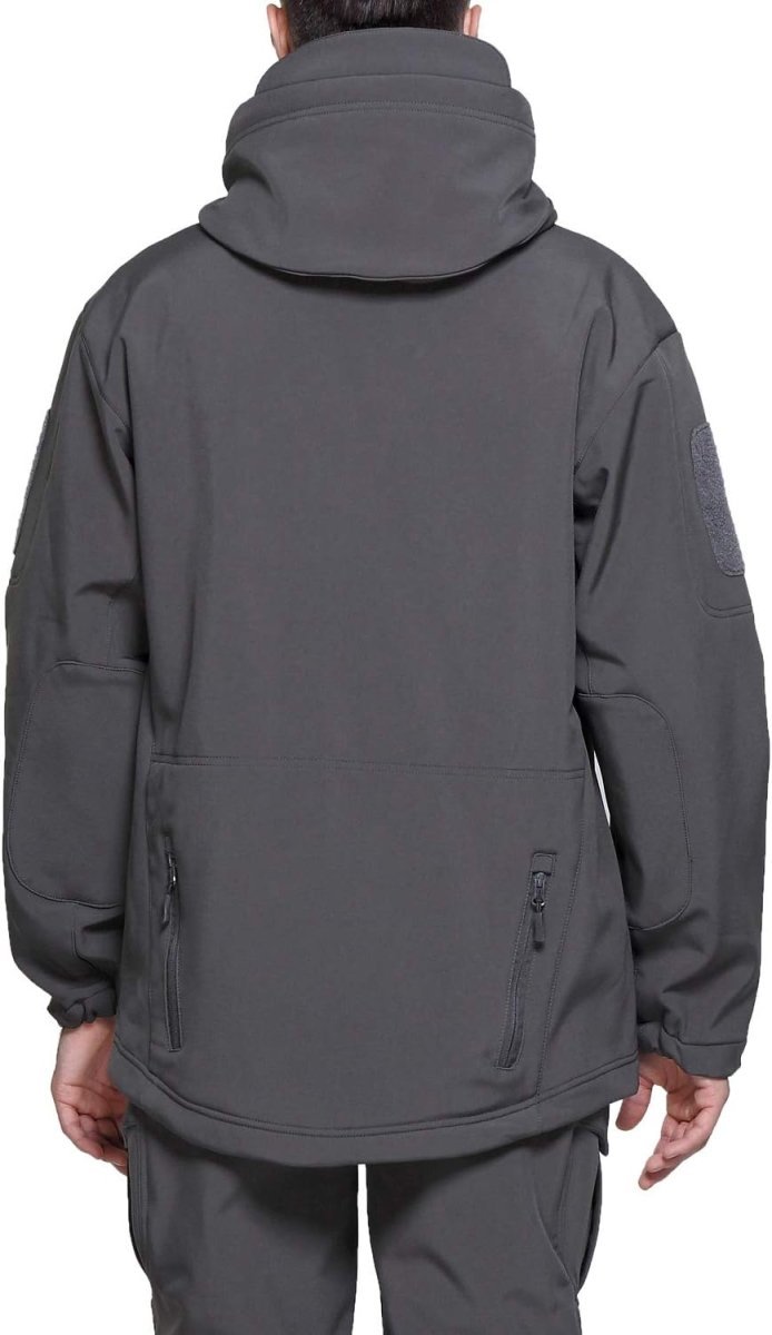 Laad afbeelding in Galerijviewer, Een persoon is van achteren te zien in een donkergrijze capuchonjas en bijpassende broek. De camouflage tactische heren softshell jas bevat zakken en mouwpatches, die stijl combineren met functionaliteit voor outdooravonturen.
