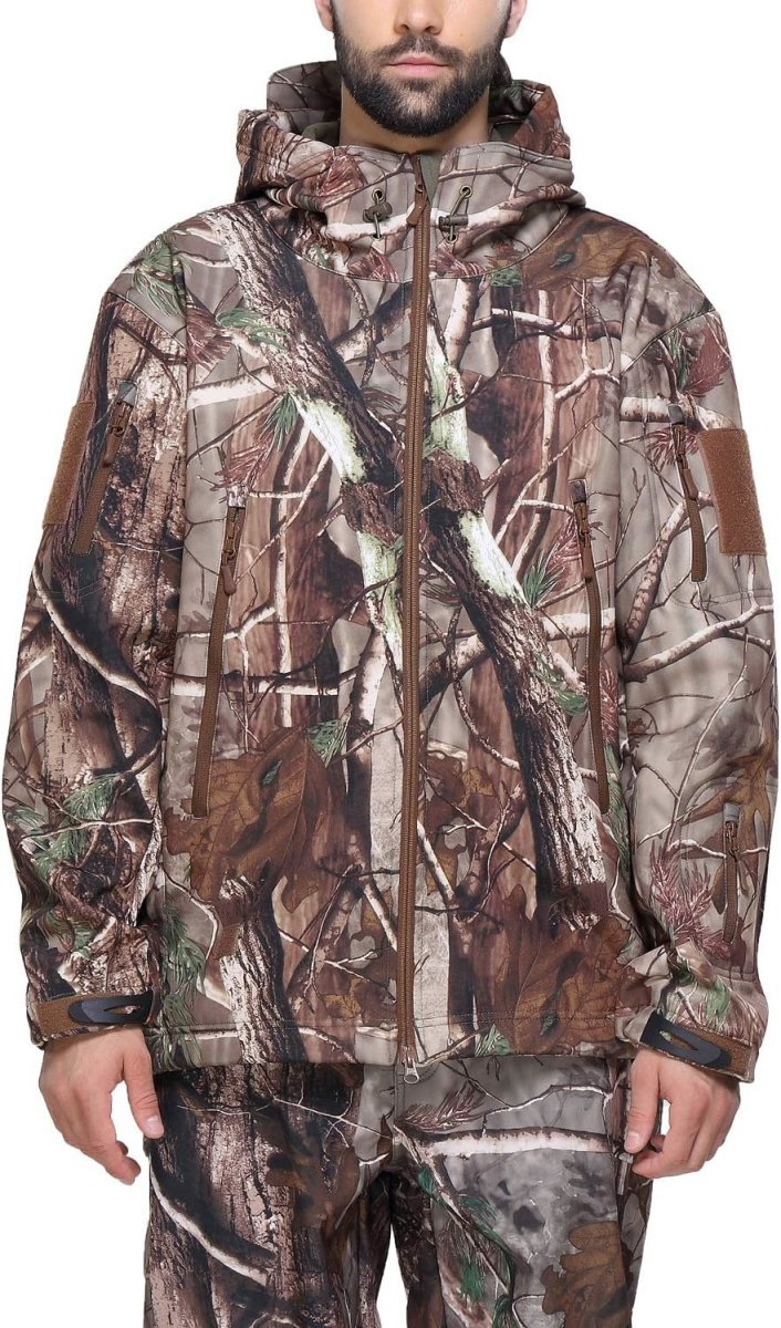 Laad afbeelding in Galerijviewer, Een persoon die een Camouflage tactische heren softshell jas draagt met bijpassende broek met bosmotief staat zelfverzekerd tegen een effen achtergrond.
