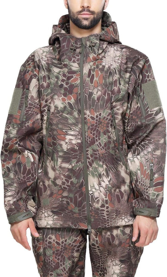 Persoon draagt een Camouflage tactische heren softshell jas en broek, met een camouflagepatroon in de kleuren groen, bruin en beige.