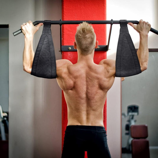 Iemand met kort haar doet pull-ups met behulp van het "Ontdek de kracht van de buikspierlussen en krijg de buik van je dromen!" bandjes om hun rompspieren te versterken voor een gewenst sixpack in de sportschool.
