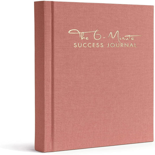 Een roze hardcoverboek, "Het 6-Minute Success Journal: Transformeer je Leven met Slechts 6 Minuten Per Dag!", is voorzien van gouden letters en combineert mindfulness met productiviteit om uw dagelijkse routine te verbeteren.