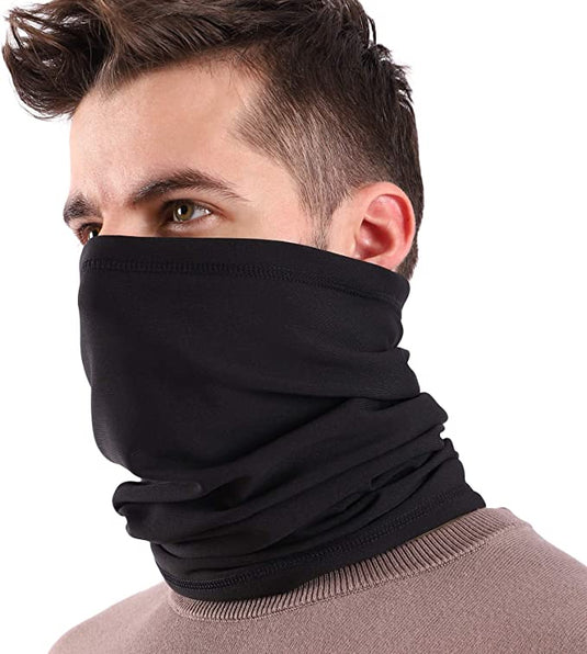 Een persoon draagt een zwarte nekwarmer, die de multifunctionaliteit en kwaliteit van ons gezichtsmasker, gemaakt van hoogwaardige stof, laat zien, die het onderste deel van het gezicht bedekt. Met kort bruin haar en een rozebruin bovenstuk poseren ze tegen een effen achtergrond.