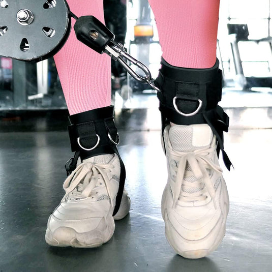 Close-up van een persoon in roze leggings en witte sneakers met "Verstevig je bilspieren, heupen, dijen en kuiten met de fitness enkelriem!" bandjes gemaakt van hoogwaardig neopreen, verbonden met fitnessapparatuur.