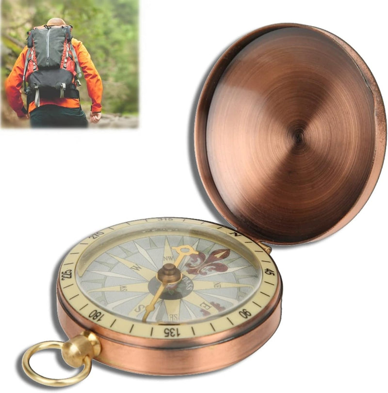 Laad afbeelding in Galerijviewer, Een &quot;Vintage koper kompas: een klassiek hulpmiddel voor outdoorliefhebbers&quot; is open en toont de hoofdrichtingen. In de buurt doorkruist een wandelaar met een oranje rugzak een met bomen omzoomd pad, vertrouwend op het compacte en lichte ontwerp voor moeiteloze navigatie.
