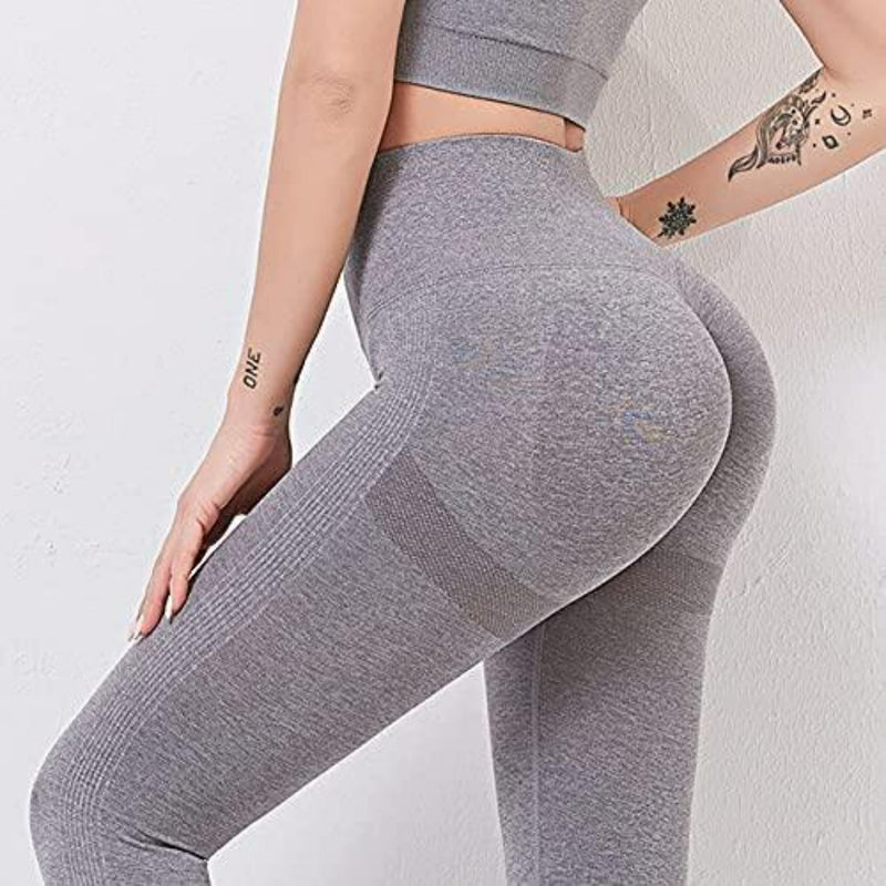 Laad afbeelding in Galerijviewer, Een persoon modelleert in een grijze, naadloze crop top met dames yoga legging met een hoog getailleerde tailleband tegen een witte achtergrond, met tatoeages op hun handen en arm voor een artistieke flair. Ontdek de perfecte mix van stijl en comfort met onze yoga leggings voor dames!.

