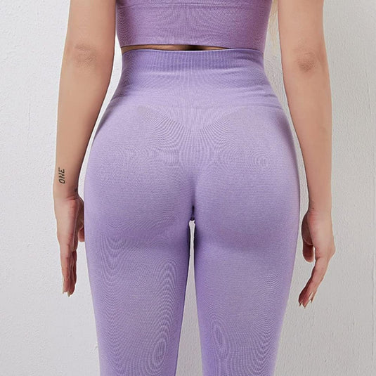 Achteraanzicht van een persoon die een "de perfecte balans van stijl en comfort" yogalegging draagt, in het paars met een hoog getaillleerde tailleband tegen een effen achtergrond.