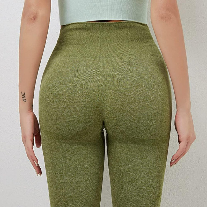 Laad afbeelding in Galerijviewer, Een persoon poseert tegen een effen achtergrond in groene high-waisted leggings, met een woordtattoo op hun arm. De hoog getailleerde tailleband zorgt voor comfort en stijl, waardoor deze leggings perfect zijn voor elke sessie. Ontdek de perfecte balans met onze yogaleggings voor dames!.
