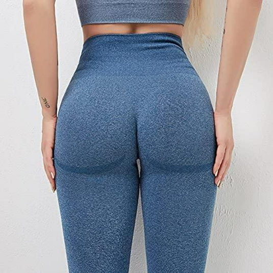 Een persoon die "Ontdek de perfecte balans van stijl en comfort met onze yogaleggings voor dames draagt!" in blauw vanaf de achterkant, met accent op een hoog getailleerde tailleband, met handen op de heupen en een tatoeage op de linkerpols.
