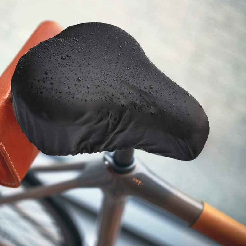 Laad afbeelding in Galerijviewer, De Geniet van comfortabel fietsen zadelhoes, met zijn strakke zwarte hoes, glanst onder waterdruppels en toont zijn waterdichte design. Een vleugje bruin leer voegt elegantie toe, waardoor het perfect is voor stadsfietsers die op zoek zijn naar stijl en functionaliteit, terwijl het moderne fietscomfort belichaamt.
